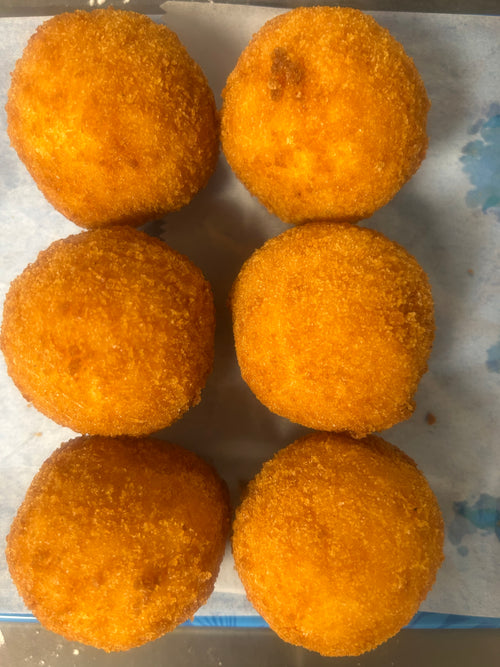 Six golden-brown fried rice balls on a white paper-lined tray.
